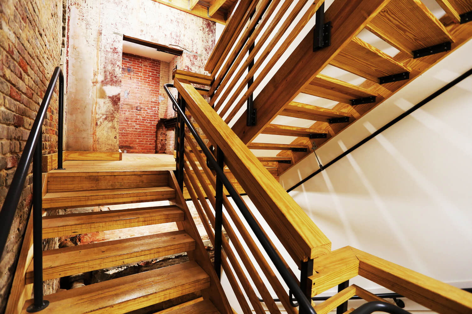 District 36 Lofts Designed by Foshee Architecture - Rear Wood Stairs with Exposed Brick Walls